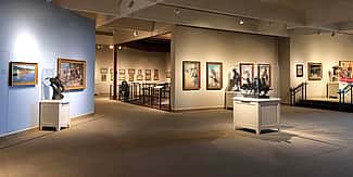 Interior of the Whitney Western Art Museum, showcasing a variety of Western art pieces, including paintings and sculptures, in a well-lit gallery setting.