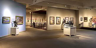 Interior of the Whitney Western Art Museum, showcasing a variety of Western art pieces, including paintings and sculptures, in a well-lit gallery setting.