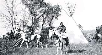 Joseph Henry Sharp (1859 – 1953), "Crow Indians on Horses in Tipi Village." Black and white photograph.