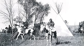 Joseph Henry Sharp (1859 – 1953), "Crow Indians on Horses in Tipi Village." Black and white photograph.