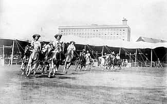 Etheyle Parry and Juanita Parry lead cowgirls riding horses around the Buffalo Bill's Wild West arena. MS 6 William F. Cody Collection, McCracken Research Library. P.69.1304