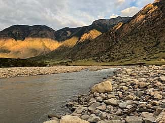 Mountains in background with river and river rock in foreground. Photo by George Miller.