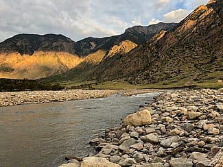 Mountains in background with river and river rock in foreground. Photo by George Miller.