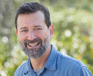Dr. Scott Wing, blue shirt, greenery background. Photo by Jame Kegley for the Smithsonian.