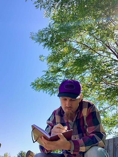 Evan Wambeke, writing outdoors.