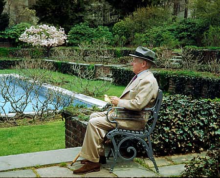 RW.R. Coe at Oyster Bay, sitting outside near pool with green vegetation.