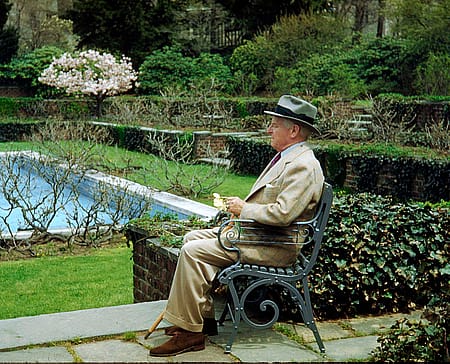 RW.R. Coe at Oyster Bay, sitting outside near pool with green vegetation.