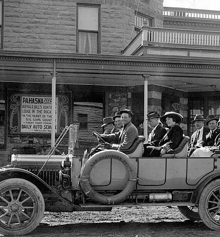Kid Wilson, driving his 1915 White Motor Co. 45-C touring car, with a load of tourists bound for Pahaska Tepee, leaving from in front of the Irma Hotel. Wilson ran his touring company from the Park Garage, across Sheridan Ave. from the Irma; that building eventually became the Cody Theater. Coe family archives photo, used with permission.
