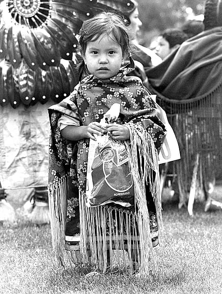 James Bama (1926 – 2022), Untitled [Young Girl at Powwow with Doritos], n.d. Black and white photograph, 14 x 11 inches. Buffalo Bill Center of the West, Cody, WY. MS 243 James Bama Collection, McCracken Research Library. P.243.49527 