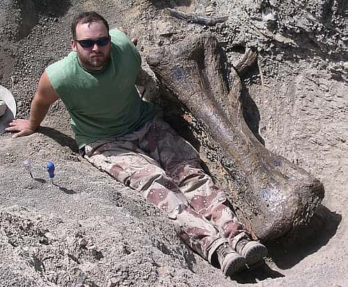 Jason Schein in the field, posing with a tibia from Dreadnaughtus in Patagonian Argentina. Courtesy photo.