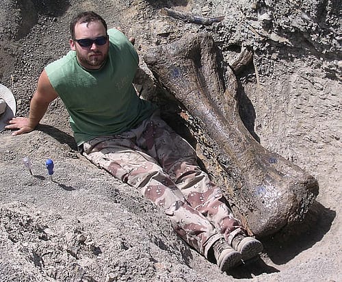 Jason Schein in the field, posing with a tibia from Dreadnaughtus in Patagonian Argentina. Courtesy photo.