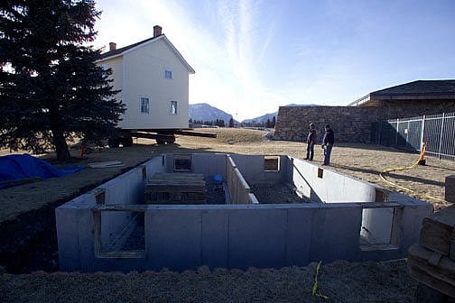 A new foundation, with the house approaching on the flatbed, January 2004.