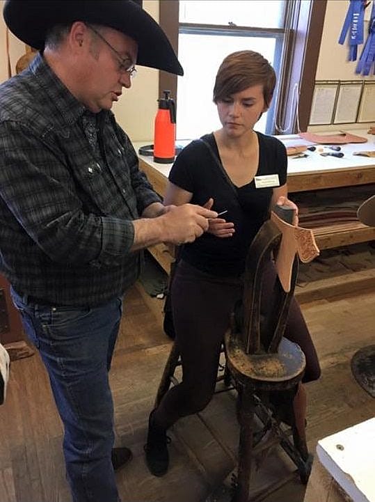 Conservation intern Nicole Schmidt uses an awl to prepare a leather scabbard for sewing. 
