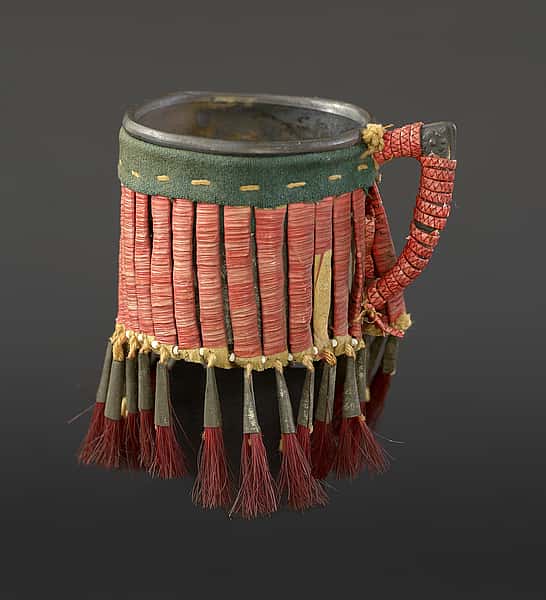 Cup, Lakota (Sioux), Northern Plains, ca.1900. Metal, rawhide, tin cones, glass beads, porcupine quills, tanned hide, wool cloth, cotton thread, dyed horse hair; NA.506.146. Courtesy of the Plains Indian Museum.