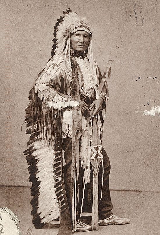 Black and white postcard. Touch the Clouds wearing war bonnet and traditional regalia. Photo attributed to Julius Ulke. The Paul Dyck Plains Indian Buffalo Culture Collection, acquired through the generosity of the Dyck family and additional gifts of the Nielson Family and the Estate of Margaret S. Coe. P.320.429