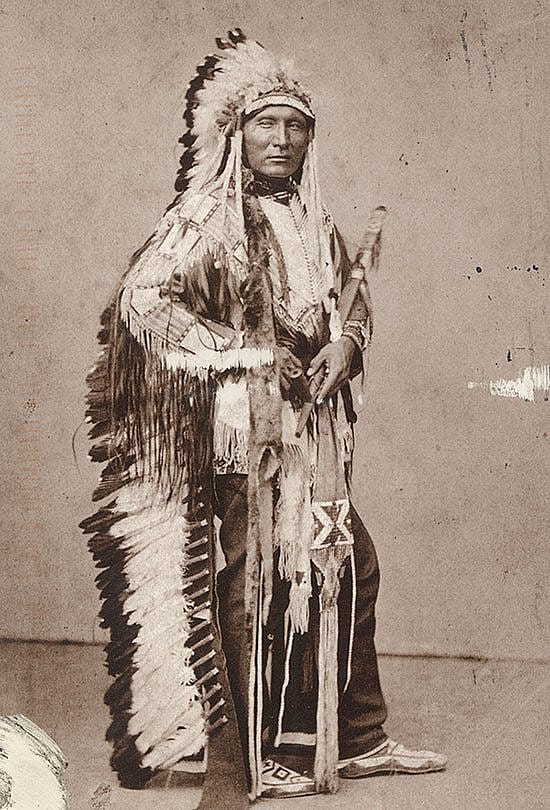 Black and white postcard. Touch the Clouds wearing war bonnet and traditional regalia. Photo attributed to Julius Ulke. The Paul Dyck Plains Indian Buffalo Culture Collection, acquired through the generosity of the Dyck family and additional gifts of the Nielson Family and the Estate of Margaret S. Coe. P.320.429