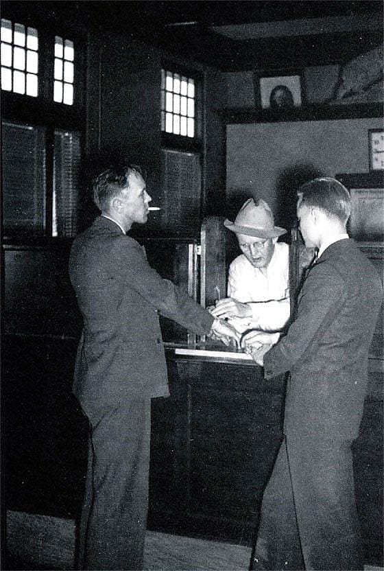 Bank president Bob Nelson and cashier Maurice Knutson re-enact the bank robbery for photographers. Kershaw photo.