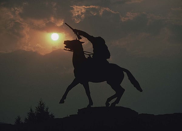 Buffalo Bill - The Scout sculpture silhouetted against a smoky sky with orange sun. SL.301.10.423
