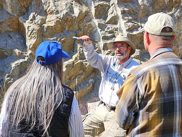 Larry Oliveria holds up a rock hammer during a geology field trip.