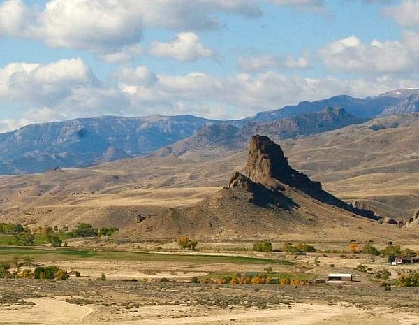 Landscape photograph of rock formation Castle Rock with valley in foreground and mountains in background.