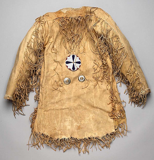Mountain man's fringe leather jerkin shirt decorated with two nickel conchas and a large beaded rosette, undated. Gift of Richard W. Leche. NA.202.588