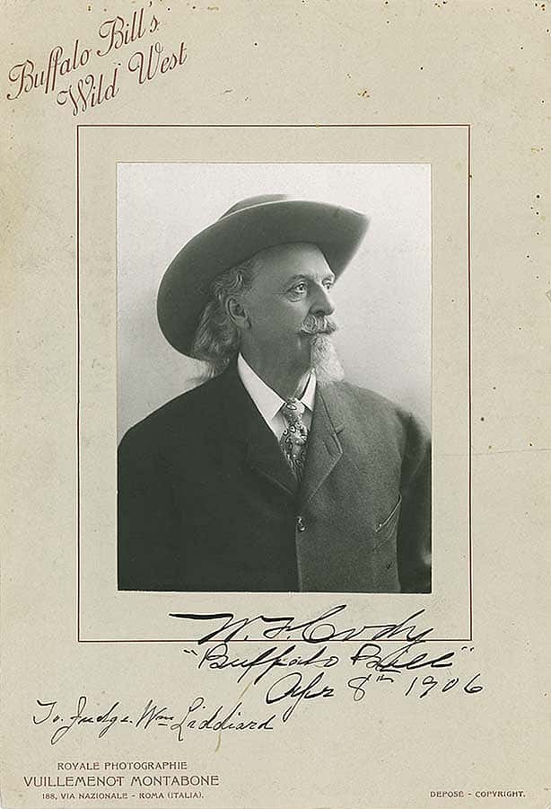 Formal portrait of Buffalo Bill Cody from 1906, featuring him in a suit and hat, with autograph, under the title "Buffalo Bill’s Wild West.