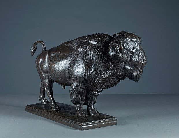Bronze sculpture of a bison viewed from a different angle, highlighting its strong stance, detailed fur texture, and muscular form on a rectangular base.