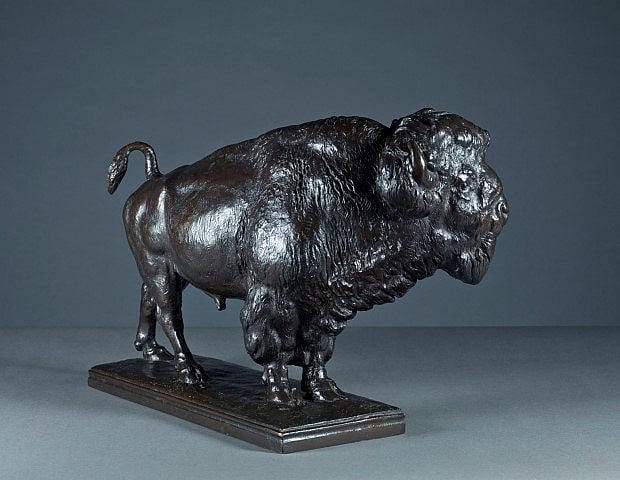 Bronze sculpture of a bison viewed from a different angle, highlighting its strong stance, detailed fur texture, and muscular form on a rectangular base.