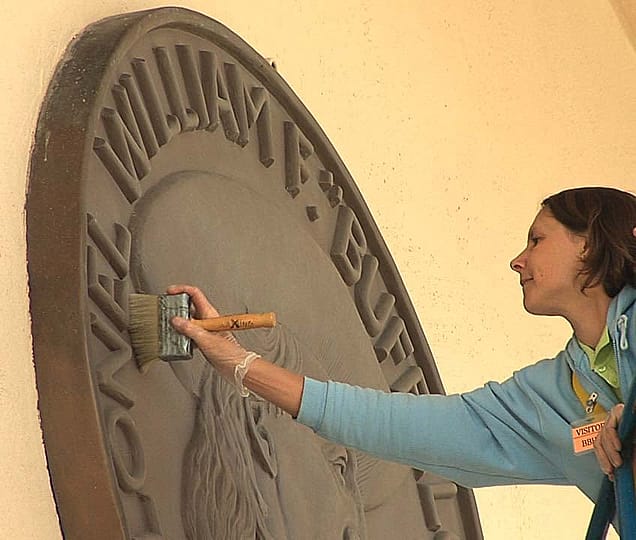 Marianne Marti cleaning bronze medallion.