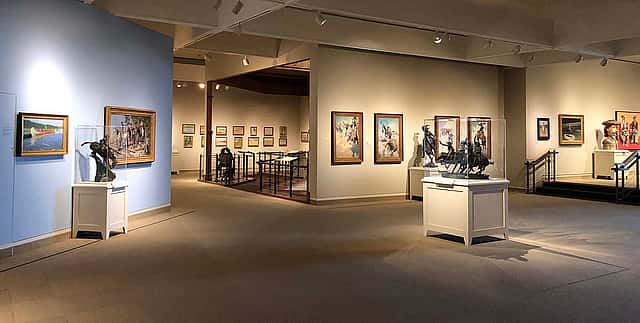 Interior of the Whitney Western Art Museum, showcasing a variety of Western art pieces, including paintings and sculptures, in a well-lit gallery setting.