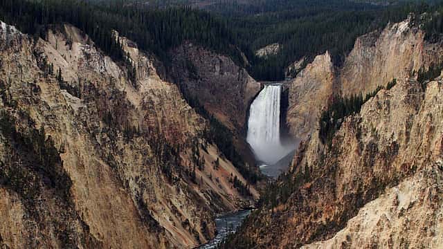 Breathtaking panorama of Lower Falls at Yellowstone, where water cascades powerfully down steep, colorful canyon cliffs.