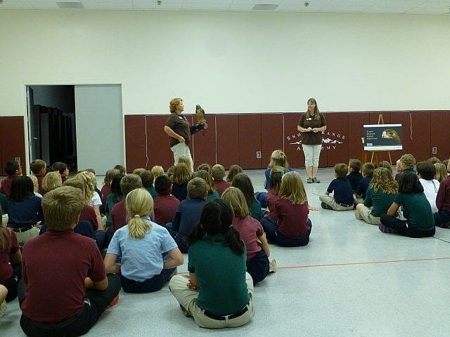 Presenter and handler with red-tailed hawk and group of students.