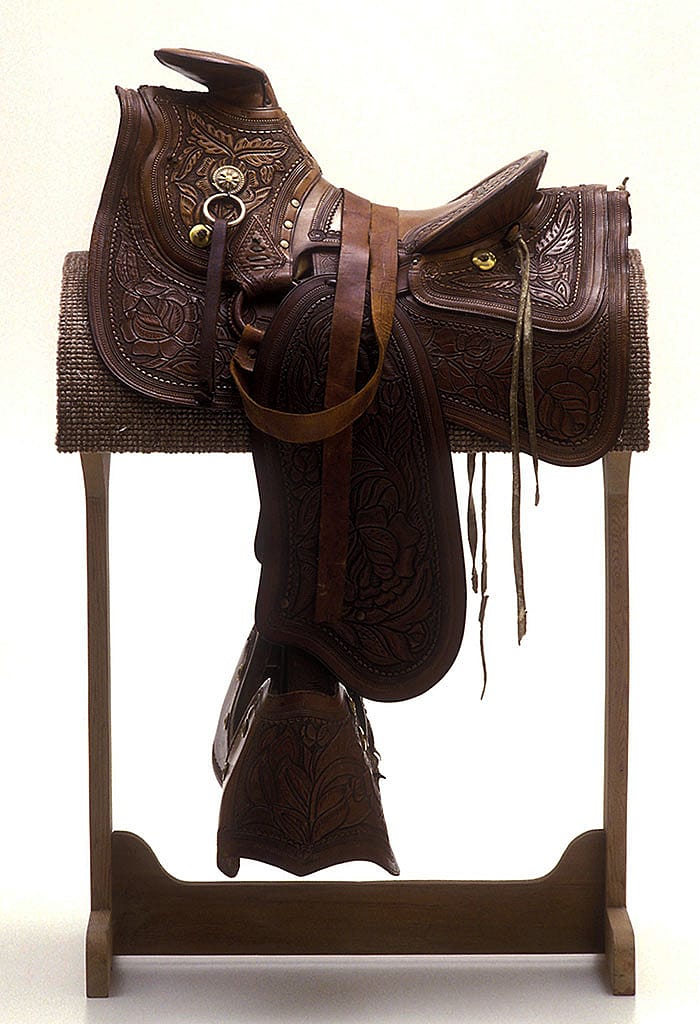 This A-frame saddle with tapaderos was made between 1850 and 1890. Note the carving style. These earlier patterns incorporated large floral elements. Gift of the Coe Foundation. 1.67.331