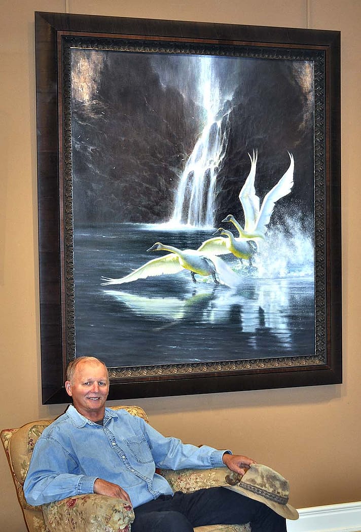 Artist M.C. Poulsen poses with his "Swans at Fairy Falls," an oil on canvas painting from 2021.