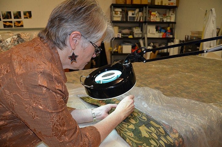 In conservation work, magnification helps us to see the tiny breaks in the wool and place the restoration thread.