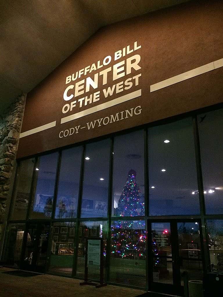 The Buffalo Bill Center of the West’s lighted Christmas tree shines through the buildings front facade.