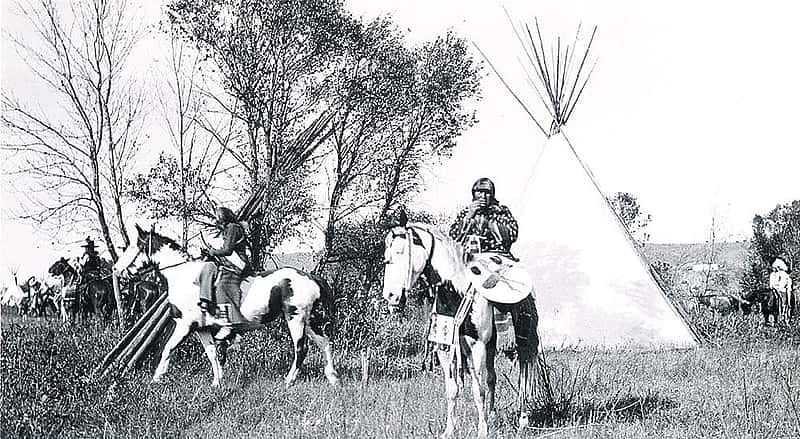 Joseph Henry Sharp (1859 – 1953), "Crow Indians on Horses in Tipi Village." Black and white photograph.