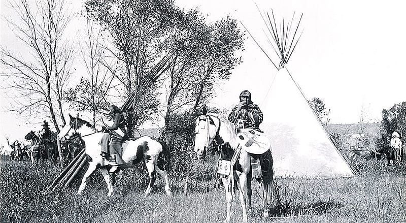 Joseph Henry Sharp (1859 – 1953), "Crow Indians on Horses in Tipi Village." Black and white photograph.