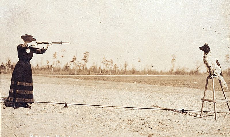 Annie Oakley plans to shoot an apple off the head of her dog Dave in this postcard image. P.94.1
