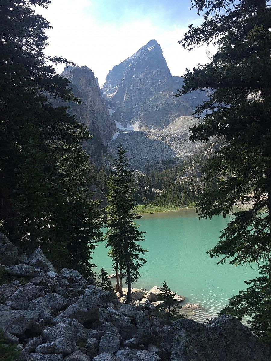 Stunning view of Delta Lake’s turquoise waters surrounded by rugged mountain peaks and alpine forest beneath the towering Grand Teton.