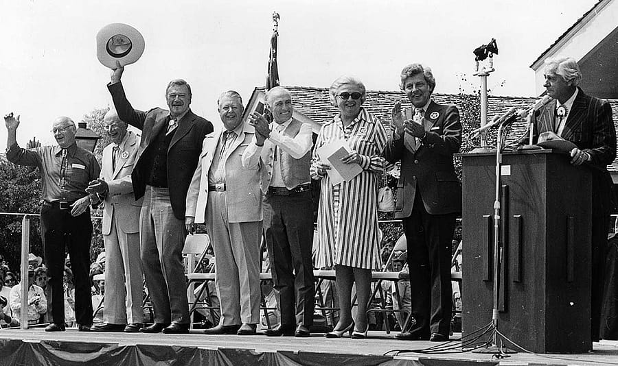 (L-R) R.N. Buswell, Harold McCracken, John Wayne, William E. Talley, Cliff Hansen, Margaret "Peg" Coe, Gale McGee, and Curt Gowdy, July 4, 1976, on the occasion of America’s Bicentennial and the dedication of the Winchester Arms Museum at the then Buffalo Bill Historical Center. MS 41 Mary Jester Allen Collection, McCracken Research Library. P.41.505
