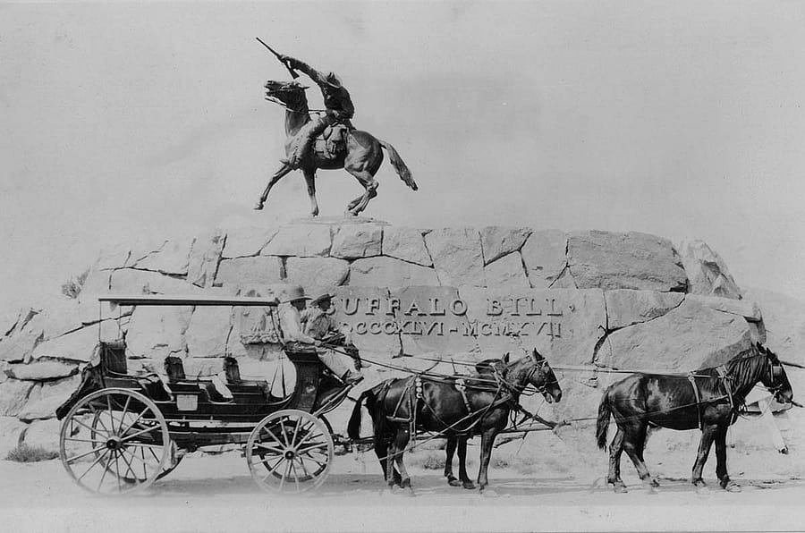 A coach stops in front of the statue "Buffalo Bill - The Scout" by Gertrude Vanderbilt Whitney, ca. 1924–1940. MS 327 James Wojtowicz Collection, McCracken Research Library. MS 327.07.29.001.01