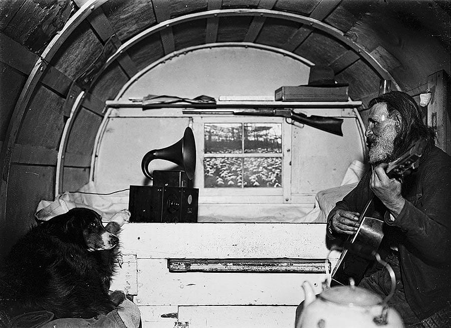 Sheepherder Jack Scott playing guitar in wagon with do, ca. 1930. Charles J. Belden photograph; glass plate negative. MS 3 Charles Belden Collection. PN.67.370
