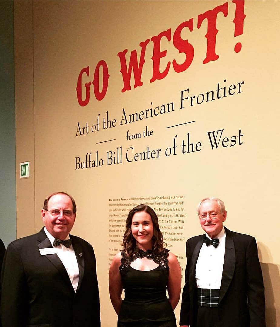 Two men and a woman dressed formally at an exhibition opening: "Go West: Art of the American Frontier"