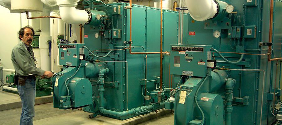 Operating Engineer Phil Anthony is pictured with boilers that will take on the load of heating older parts of the Center, areas where inefficient and outdated equipment will be scrapped.