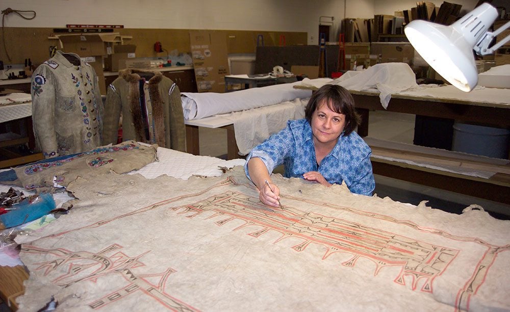 Buffalo Bill Center of the West Conservator Beverly Perkins works on a painted hide from the Plains Indian Museum collection.