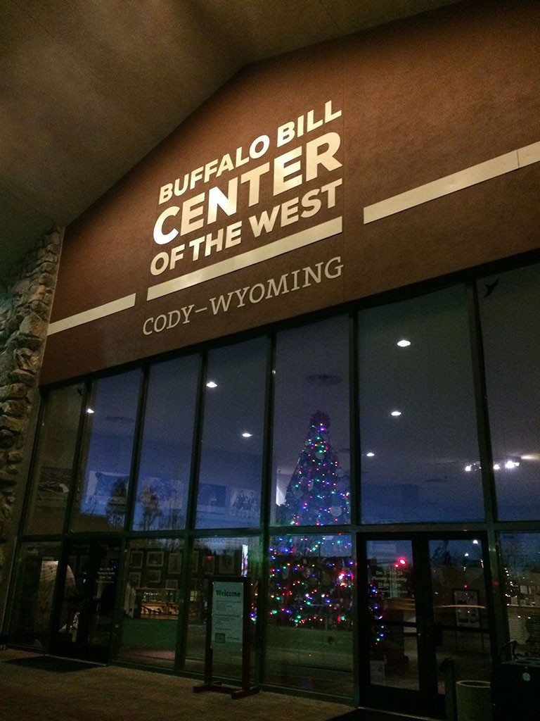 The Buffalo Bill Center of the West’s lighted Christmas tree shines through the buildings front facade.