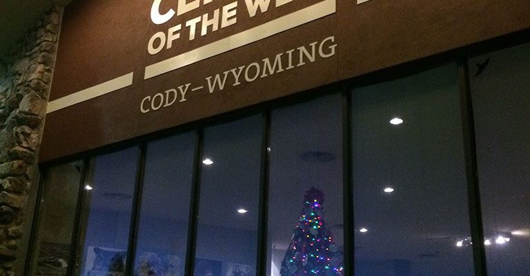 The Buffalo Bill Center of the West’s lighted Christmas tree shines through the buildings front facade.
