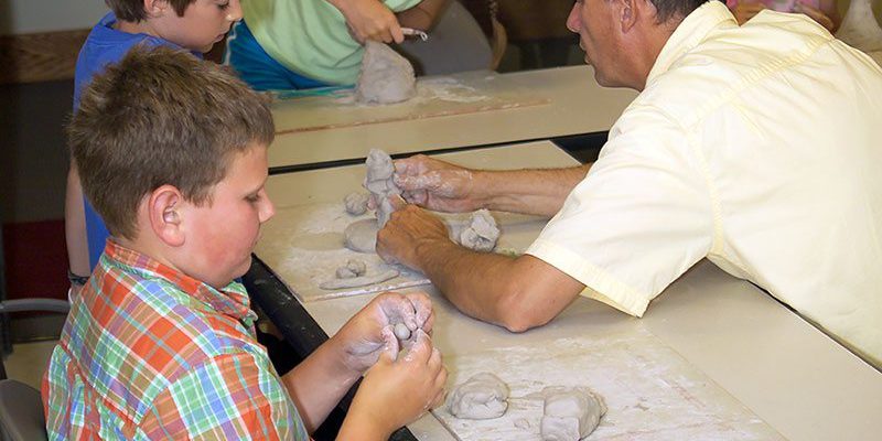 Jeff Rudolf teaching kids to sculpt with clay.