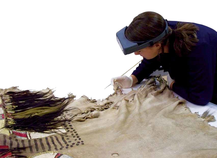 Tara Griffin, who served as a conservation intern in 2010, begins her work with a close examination of an artifact from the Paul Dyck Plains Indian Buffalo Culture Collection. Man's shirt, Upper Missouri River, ca. 1840s. The Paul Dyck Plains Indian Buffalo Culture Collection, acquired through the generosity of the Dyck family and additional gifts of the Nielson Family and the Estate of Margaret S. Coe. NA.202.1218